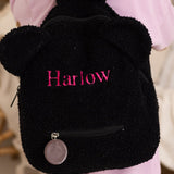 Child wearing a black backpack with 'Harlow' embroidered on it, standing indoors.  The Bear Backpack Bag Personalised Cozy Crew Club Bags mora-uk.myshopify.com the-bear-backpack-bag   10off, 20off, acc, accessories, accessory, allproducts, baby, back pack, backpack, bag, beige, BFCM-20, BFCM-25, BFCM20, birthday, china, CHRISTMAS20, clothing, daywear, embroidery, kids, LINECARD, lunch box, new in, PADDY10, personalised, school, set, slip on, whatnot, WINTER20, zero